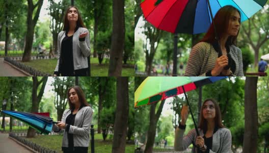 美丽的女人检查是否下雨，然后打开她的五颜六色的伞站在城市公园。Slowmotion拍摄高清在线视频素材下载