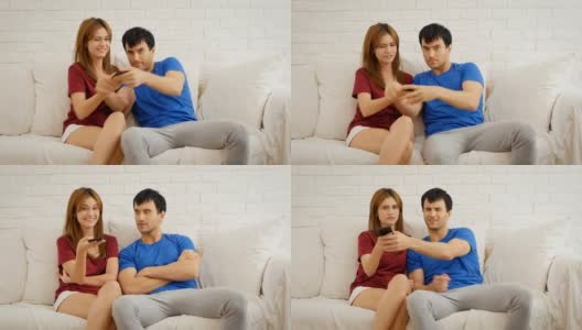 一对年轻夫妇在起居室看电视，为了抢遥控器而吵架高清在线视频素材下载