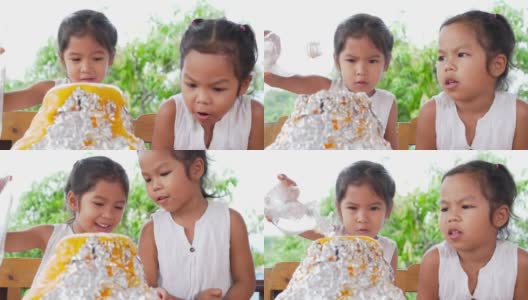 两个亚洲小女孩在自己家里的桌子上做小苏打和醋火山实验，慢镜头每秒100帧高清在线视频素材下载