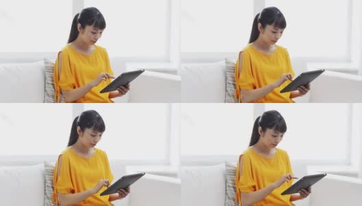 快乐的年轻亚洲女人在家里有平板电脑高清在线视频素材下载