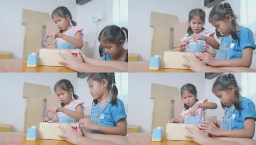 两个小女孩帮助家长用胶带把产品包装好，然后用快乐的心情将产品送到网上顾客手中。高清在线视频素材下载
