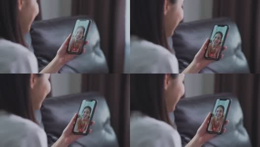 开朗美丽的亚洲女人在白色t恤做视频通话在线与朋友聊天和手触摸数码平板电脑在沙发上的相机。高清在线视频素材下载