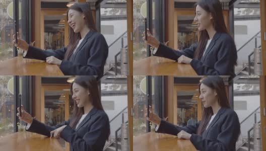 迷人的年轻亚洲女子在咖啡店用智能手机视频通话高清在线视频素材下载