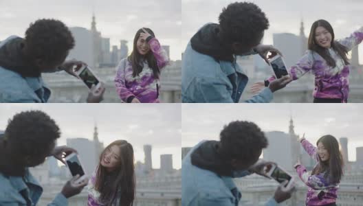 快乐的年轻亚洲女人在屋顶上摆姿势与摄影师与智能手机高清在线视频素材下载