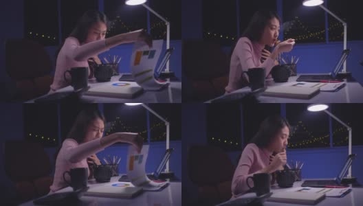 亚洲商界女性晚上在家边吃方便面边用笔记本电脑工作高清在线视频素材下载