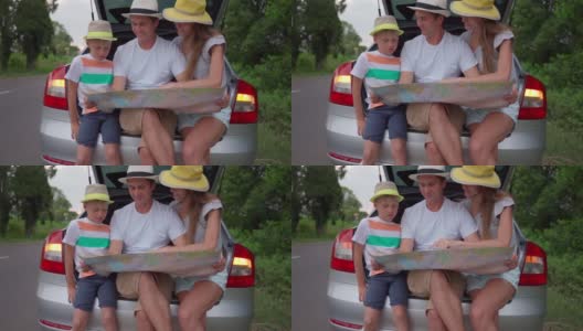 一家人坐在汽车后备箱里学习地图。坐汽车长途旅行。家庭高清在线视频素材下载