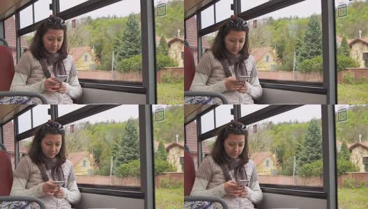 一名年轻女子在乘坐公交车时使用智能手机高清在线视频素材下载