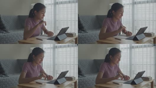 快乐的亚洲女性在家里的客厅里用平板电脑向在线家教挥手或打招呼。提出在家在线学习的概念高清在线视频素材下载