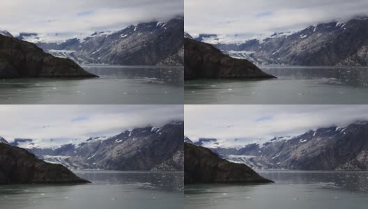 在阿拉斯加冰川湾国家公园的约翰霍普金斯冰川雕刻山的开放视图。雪山被云覆盖。高清在线视频素材下载