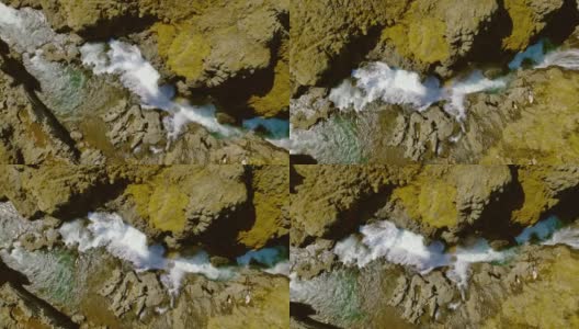 无人机从上往下拍摄被广阔的落基山脉包围的狭窄瀑布高清在线视频素材下载