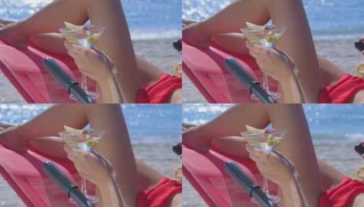女性手握马提尼与橄榄在热带海滩上的特写高清在线视频素材下载