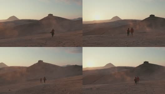 一对夫妇跑向一座山的航拍，背景是日落高清在线视频素材下载