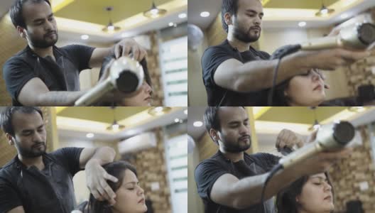 美容院的一名工作人员在给女顾客理发时正在用吹风机高清在线视频素材下载