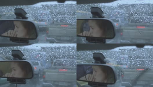 女人在雨中开车，女人的脸映照在汽车后视镜上高清在线视频素材下载