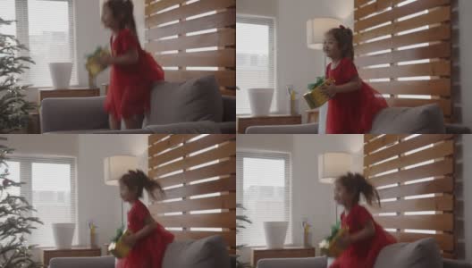 快乐的小亚洲可爱女孩跳沙发与圣诞礼物。高清在线视频素材下载