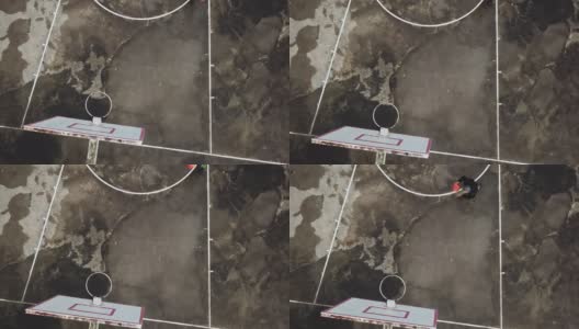 在无人机的镜头下，一名亚裔中国老人在篮球场练习篮球高清在线视频素材下载