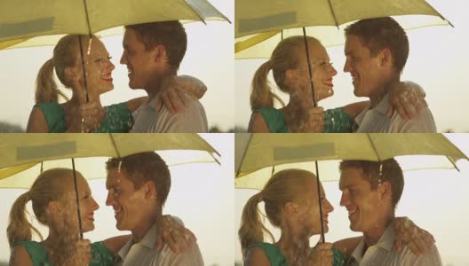 近距离观察:春雨中，一对美丽的年轻夫妇在伞下旋转。高清在线视频素材下载