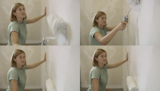 专注的女人用漆辊把墙刷成白色，慢动作高清在线视频素材下载