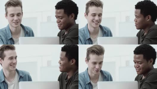 两个不同的男同学一起在笔记本电脑上做项目。年轻人看着屏幕，愉快地交谈着高清在线视频素材下载