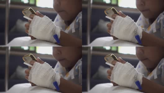 婴儿女儿在病床上使用智能手机的特写。年轻病人的放松时间。治疗室实时拍摄。高清在线视频素材下载