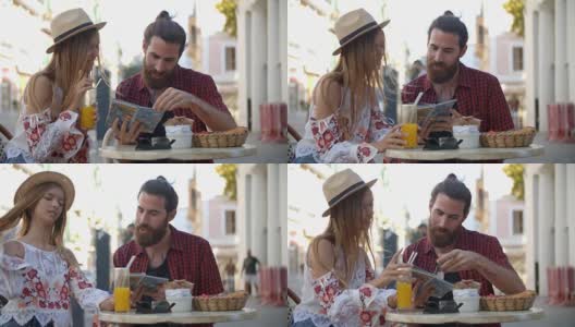 一对快乐的夫妇在度假时在咖啡馆外阅读旅游指南高清在线视频素材下载