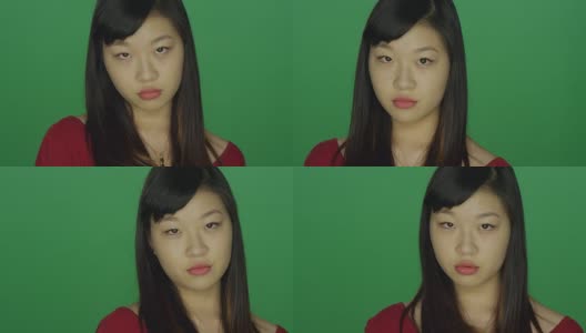 年轻的亚洲女人看起来严肃，在一个绿色屏幕的工作室背景高清在线视频素材下载