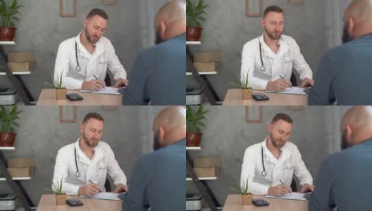 一个男人在医生的预约桌旁坐下，谈论他的健康。医生检查的概念。高清在线视频素材下载