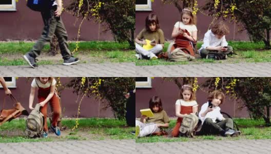 放学后，小学生们坐在草地上，从书包里拿出智能手机，玩网络游戏。网络成瘾。视频游戏高清在线视频素材下载