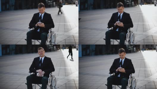 一位坐在轮椅上的年轻商人正在用他的智能手机玩或工作高清在线视频素材下载