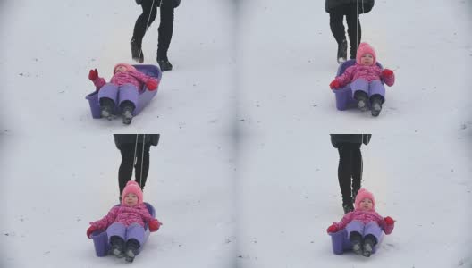 妈妈拉着雪橇和她的女儿在冬季的小径上高清在线视频素材下载