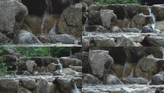 小瀑布在树林中的岩石之间高清在线视频素材下载