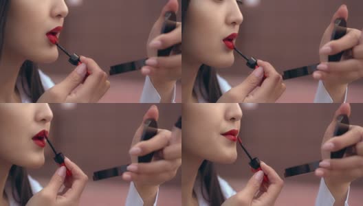 美丽的日本女孩用红色的口红涂她的嘴唇。人看起来不错。高清在线视频素材下载