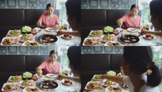 快乐的亚洲女人在热煤炉上烧烤猪肉。韩式或日式烧烤。高清在线视频素材下载