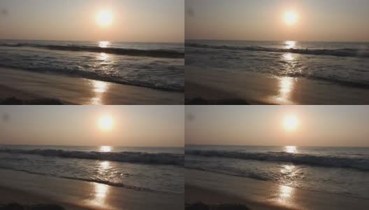 北岸的沙滩上，汹涌的海浪。泡沫和溅在海里，晴天，慢动作视频。《水面与波浪》是一段缓慢移动的视频。海面上的日出景观。海滩上金色的日出。海洋的日出。高清在线视频素材下载