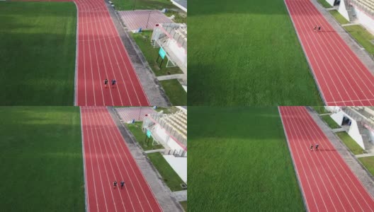 在无人机的镜头中，亚洲华人父亲站在起跑线上，在田径场看台旁边朝终点跑去高清在线视频素材下载