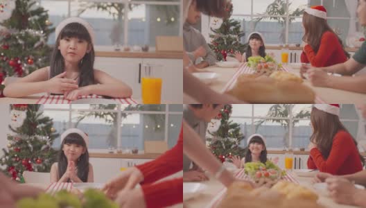 亚洲小朋友和父母一起在家享受圣诞派对。漂亮迷人的夫妇在餐桌上为年轻的女儿庆祝圣诞晚会的晚上在家里。高清在线视频素材下载