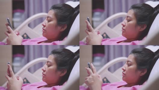 亚洲病人妇女使用触摸屏智能手机设备在医院的床上。高清在线视频素材下载