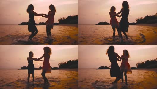 夕阳西下，两个快乐的女孩在沙滩上手拉手跳舞高清在线视频素材下载