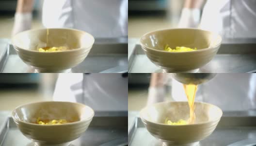 厨师在厨房把汤倒在面碗上的慢镜头高清在线视频素材下载