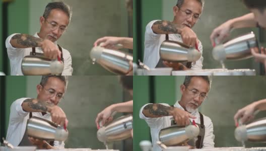 专业亚洲华人高级男咖啡师品级员将热水倒入陶瓷咖啡杯中，准备拔杯咖啡品质测试高清在线视频素材下载