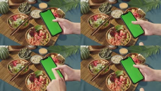 夏威夷戳碗，拿着彩色绿色屏幕的智能手机特写。由切成片的蔬菜、海鲜和绿叶植物制成的熟戳。健康的素食。亚洲素食生食，筷子高清在线视频素材下载