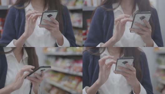 一个女人用智能手机搜索店内促销信息的特写镜头。高清在线视频素材下载