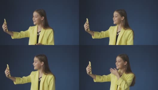 年轻女孩与朋友聊天与智能手机相机在蓝色的背景高清在线视频素材下载