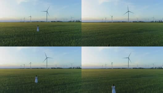 美丽的女孩站在绿色的麦田和风车高清在线视频素材下载