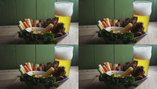一碗健康的烤鸡翅配辣汁芹菜和胡萝卜条，再来一杯啤酒高清在线视频素材下载