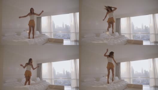 快乐的年轻女子穿着漂亮的衣服在家里的床上跳舞跳跃，慢动作高清在线视频素材下载