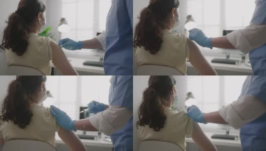在诊所或医院办公室为佩戴口罩的患者接种Covid-19或流感病毒疫苗的女护士高清在线视频素材下载