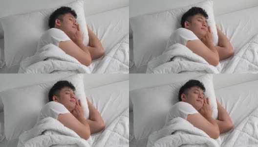 快乐的亚洲年轻人早上睡在舒适的床上。高清在线视频素材下载