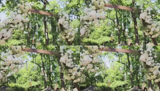 优雅的婚礼拱门与鲜花，花瓶背景的树木。的婚礼。婚礼仪式。拱门。拱门上装饰着粉红色和白色的花朵，矗立在树林里。高清在线视频素材下载