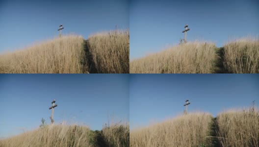 一个拿着相机的人爬上一座山上，山上有一个木十字架高清在线视频素材下载